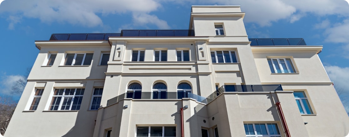 Restauruotas šviesus klasikinio stiliaus pastatas giedro dangaus fone